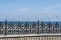 Blue see behind the azure black forged fence with barbed wire Royalty Free Stock Photo