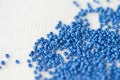 Blue seed beads scattered on a white textile background closeup. Handmade concept Royalty Free Stock Photo