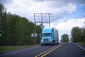 Blue semi truck with trailer on green trees highway