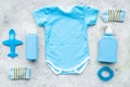 Blue set for newborn boy. Baby bodysuit, socks, airplan toy, oap and powder on grey background top view