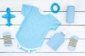 Blue set for newborn boy. Baby bodysuit, socks, airplan toy, oap and powder on white wooden background top view