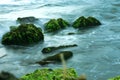 Blue Shallow Sea Waves and Green Rocks. Royalty Free Stock Photo