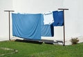 Blue sheets and white laundry hanging out to dry on the fixed drying rack in the home garden. Royalty Free Stock Photo