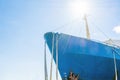 Blue ship`s nose on a blue sky background. Ship`s ropes. Bright sun above the deck.