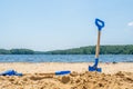 Kids beach tools blue shovel on blue water lake.