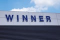 Blue sign on the wall of a building that says Winner in blue letters