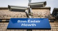 Blue signs showing Howth train station Bin Eadair with platform surveillance cameras