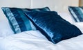 Blue silky hotel room bedding pillows and sheets on bed.