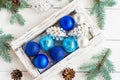 Blue, silver Christmas balls in a wooden box on a white wooden background. top view Royalty Free Stock Photo