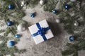 Blue and silver Christmas baubles and a gift on a soft feathery surface in front of defocused blue and white lights Royalty Free Stock Photo