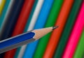 Blue and silver striped wood pencil crayon held in front of a row of pencils Royalty Free Stock Photo