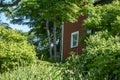New England style red barn in Groton, Ma surrounded by early summer time green leavesio