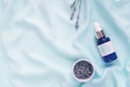 Blue skincare bottle and lavender flowers on a blue silk cloth