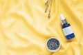 Blue skincare bottle and lavender flowers on a yellow silk cloth