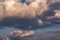 Blue sky background with evening fluffy curly rolling clouds. Good windy weather