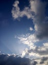 Blue sky background with the sun and rays behind the clouds. Sky heaven in portrait composition. Royalty Free Stock Photo