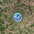 Blue sky ball in middle of swirling green field. Inversion of tiny planet transformation of spherical panorama 360 degrees.