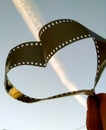 Blue sky with a cloud from an airplane and a film from a camera in the form of a heart Royalty Free Stock Photo