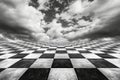 A blue sky with clouds above an abstract checkerboard floor, symbolizing a surreal and infinite concept. Royalty Free Stock Photo