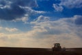 blue sky clouds above dark ploughed field with tractor Royalty Free Stock Photo