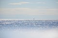 The blue sky with clouds merges on horizon with the calm, shimmering water of the lake