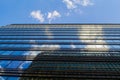 The blue sky with clouds and modern office building is reflected in the glass of Windows of a skyscraper Royalty Free Stock Photo