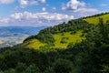 Blue sky with clouds over a mountain covered with thick bushes and trees Royalty Free Stock Photo