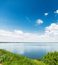 Blue sky with clouds over river and green grass Royalty Free Stock Photo