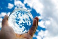 Blue sky with clouds photography in clear crystal glass ball holding in hand. Royalty Free Stock Photo