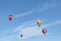 Blue sky and clouds, with several colourful hot-air balloons floating