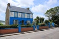 Blue sky with clouds and a striking blue house in the village Dingle in county Kerry in Ireland in the summer.