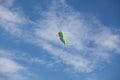 Blue sky with clouds. Summer day. Colorful rainbow kite hovers in the air high in the sky Royalty Free Stock Photo