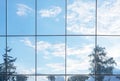 Blue sky, clouds and trees reflection in grid of glass window of modern office building. Nature vs business structures Royalty Free Stock Photo