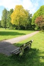 Blue sky with clouds, a wooden bench and trees in the park in spring. Royalty Free Stock Photo