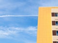 Blue sky with contrail and yellow tiled facade