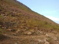 The blue sky covered the steeply hill with greenery and rocks