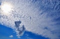 The blue sky is covered with white clouds and the sun shines through the cloud Royalty Free Stock Photo