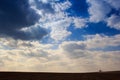 blue sky cumulus clouds above dark ploughed field Royalty Free Stock Photo