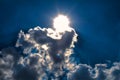 Blue sky with dazzling sun illuminating white clouds from behind Royalty Free Stock Photo