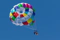 With a parachute for parasailing a couple flies through the air with blue sky in the background. Royalty Free Stock Photo