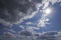 Blue sky with gray dark clouds, the sun is shining in the sky and causing a lens flare to the camera Royalty Free Stock Photo