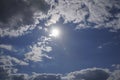 Blue sky with gray dark clouds, the sun is shining in the sky and causing a lens flare to the camera Royalty Free Stock Photo