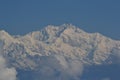 Snow clad mount Kanchenjunga standing high across blue skies