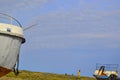 Blue sky. Old rusty abandoned boats, white ships lie on green grassy shore in the light of setting sun. Man. Lake Baikal Royalty Free Stock Photo