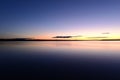 Blue sky in the orange twilight glow on horizon over calm azure water lake Royalty Free Stock Photo