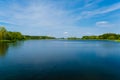 Blue sky over blue lake surrounded by green woods. Summer scenery Royalty Free Stock Photo