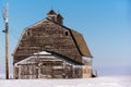 Blue sky over old, abandoned prairie barn surrounded by snow in Saskatchewan