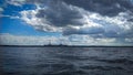 Blue sky over wavy lake landscape, nature background with heavy clouds above and visible Visaginas nuclear power plant Royalty Free Stock Photo