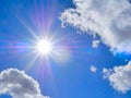 Blue sky with puffy white clouds and rays of light from sun.