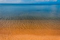 The blue sky is reflected in the clear water of the ocean. Blue water and yellow sand of Koh Samui beach Royalty Free Stock Photo